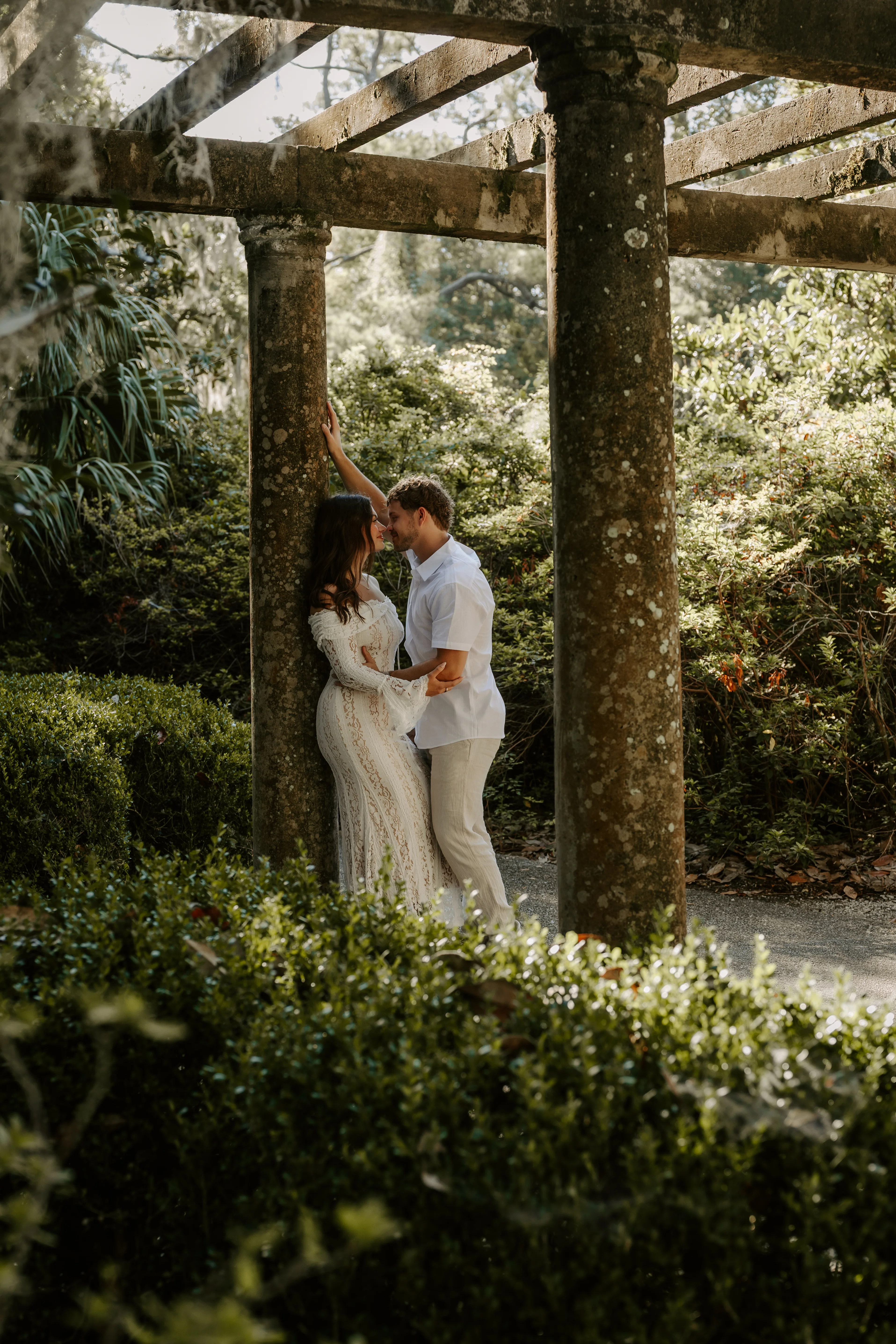 Hope and Kelly kissing beneath the stone pergola